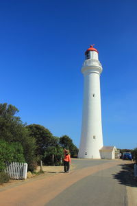 Man on lighthouse against clear blue sky