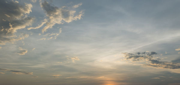 Low angle view of sunlight streaming through clouds