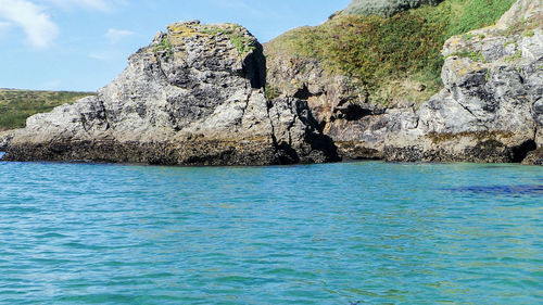 View of rocks by sea against blue sky