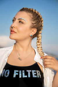 Close-up portrait of woman against blue sky