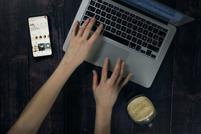 Cropped hands of woman using laptop on table