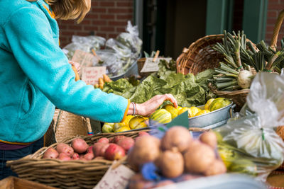 Young woman picking vegetables at farmers market