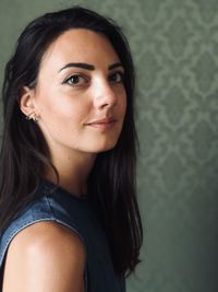 Portrait of smiling young woman against wall