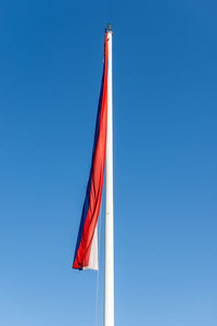 Low angle view of flags against clear blue sky