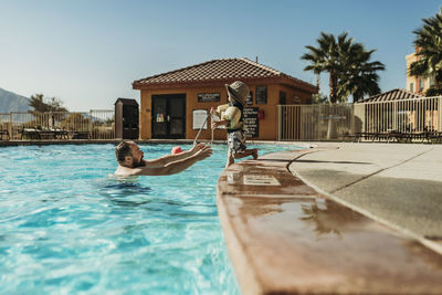 Father and toddler son playing in pool on vacation in palm springs