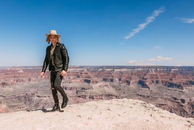 Man standing on rock against sky