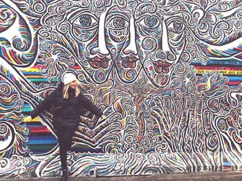 Full length of woman standing on multi colored wall
