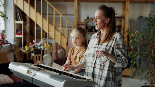 Mother teaching daughter piano at home