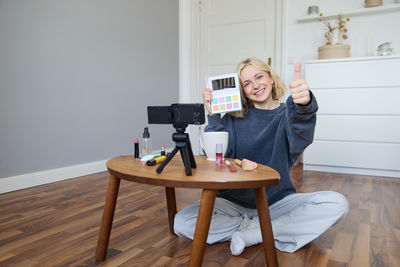 Young woman using mobile phone while sitting on table