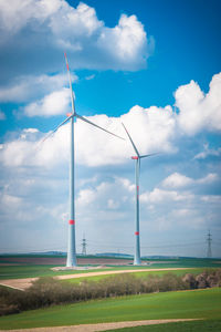 Windmills on grass against sky