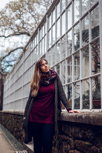 Young woman standing against building in winter