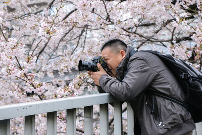 Man photographing against tree