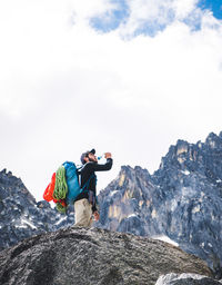 Full length of man standing on rock in mountains against sky