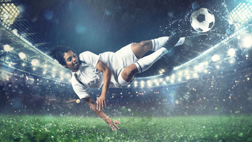 Man playing soccer ball in rain