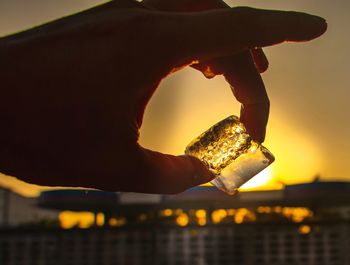 Close-up of hand holding ice cream against orange sky