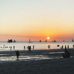 Silhouette people at beach against sky during sunset