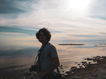 Man standing on beach against sky during sunset