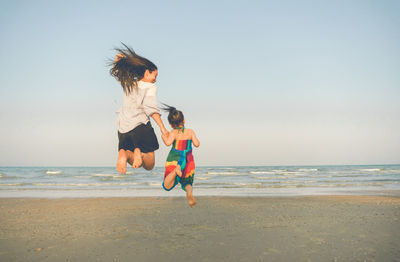 People walking on beach against clear sky