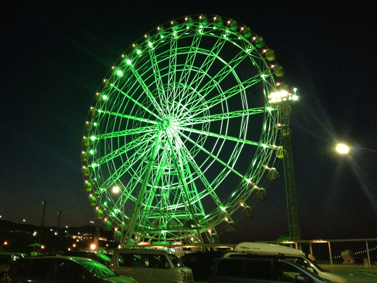 night, illuminated, ferris wheel, arts culture and entertainment, amusement park ride, amusement park, low angle view, sky, long exposure, built structure, architecture, motion, glowing, city, building exterior, firework display, outdoors, lighting equipment, blurred motion, circle