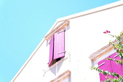 Low angle view of pink building against blue sky