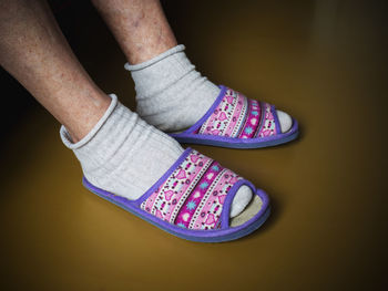 Low section of person wearing pink slippers