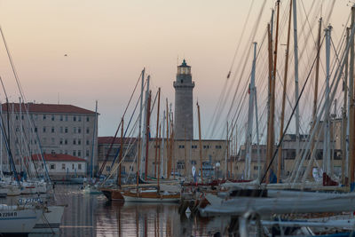 Sailboats in harbor against sky during sunset