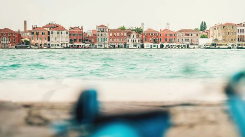 Buildings by sea against clear sky