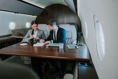 Businessman and secretary sitting in corporate jet