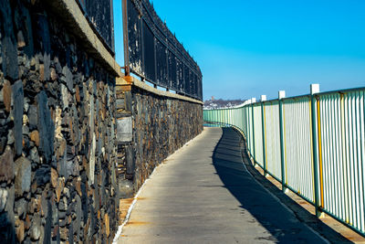 Empty footpath amidst buildings against clear blue sky