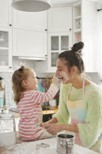 Mother and daughter preparing food in kitchen at home