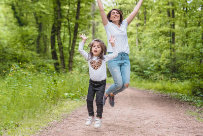 Girl and mother jumping at park