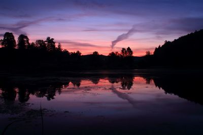 Silhouette trees by lake against sky during sunset