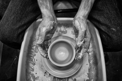 Directly above shot of potter making pot on pottery wheel in workshop