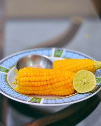 Close-up of lemon and corns in plate on table