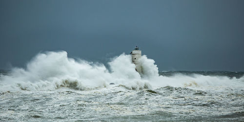 Scenic view of sea waves splashing against sky