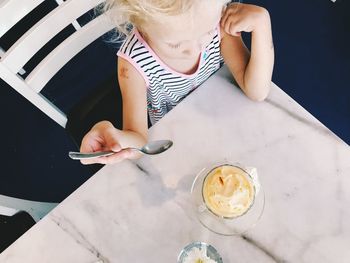 High angle view of girl eating ice cream on table at restaurant