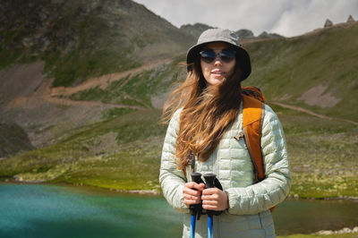 Portrait of a smiling woman resting during a mountain hike. a woman with a backpack enjoys the view