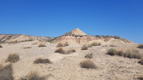 Scenic view of desert against clear blue sky