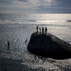 Silhouette men on beach against sky