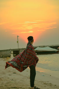 Side view of man standing at beach during sunset