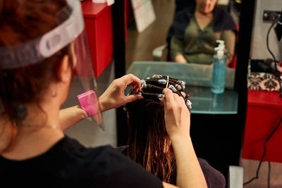 A close-up of a hairdresser combing a client with a face shield