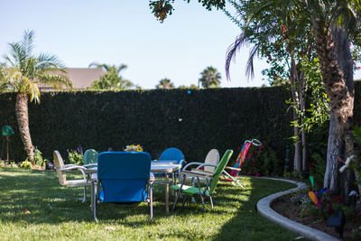 Empty chairs by swimming pool against clear sky