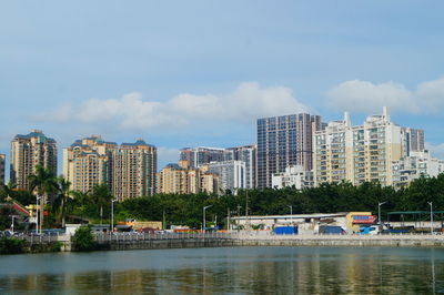 Buildings by river against sky in city