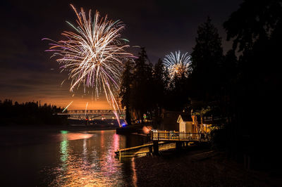 Fireworks over river against sky at dusk