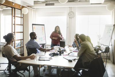 Businesswoman discussing business plan with colleagues in meeting at board room