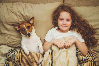 Cute little girl and puppy under quilt.