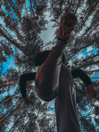 Rear view of man with arms raised in forest