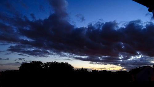 Silhouette of trees against cloudy sky