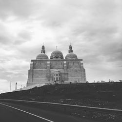 Low angle view of mosque against cloudy sky