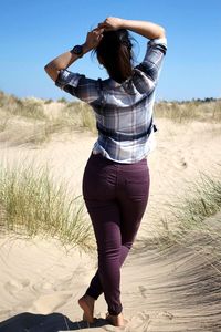 Rear view of woman standing on field against sky